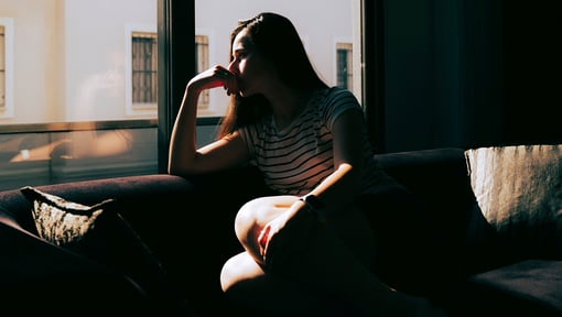 woman sitting on couch looking out window