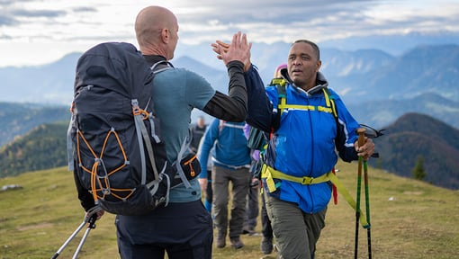 two men at a workout retreat on top of a mountain high-fiving