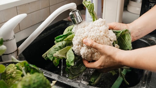 someone washing cauliflower in a sink getting ready to make a delicious nutritious meal