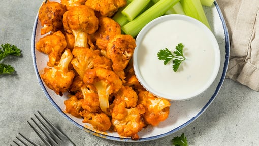 buffalo cauliflower on a plate with celery and dressing