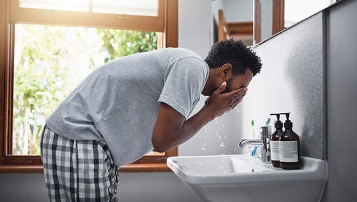 man making a mini habit of washing his face at a sink