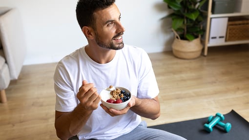 man sitting on the floor on a yoga mat enjoying a pre workout snack