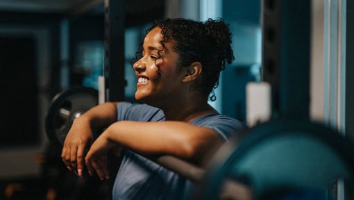 woman smiling standing over a weight bench