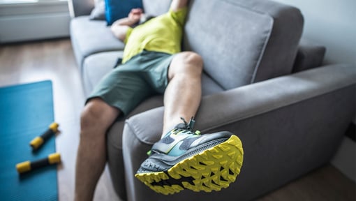 man wearing sneakers lounging on the couch after a workout