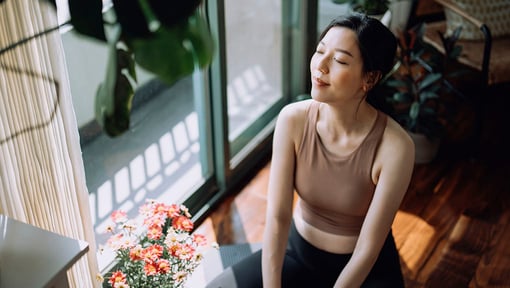 Woman relaxing by a sunny window with indoor plants.