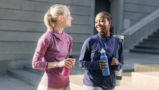 Two people wearing athletic clothing walking outdoors, taking time to disconnect from screens and engage in conversation