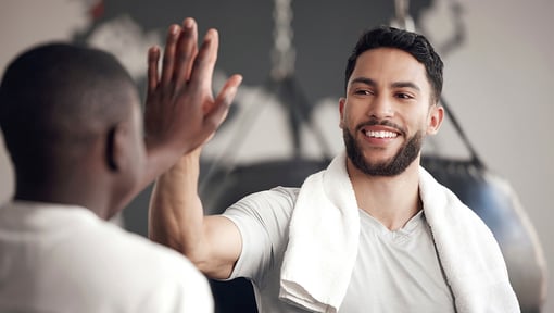 Two men giving a high-five in a gym.