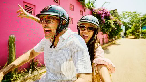 Two people on a motorized scooter taking a selfie while having a blast on vacation.