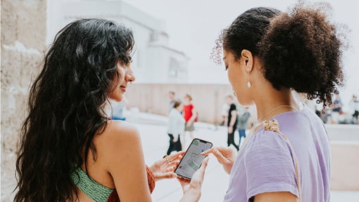 Two women sharing a new experience while on a trip, they are looking at a map on their phone.