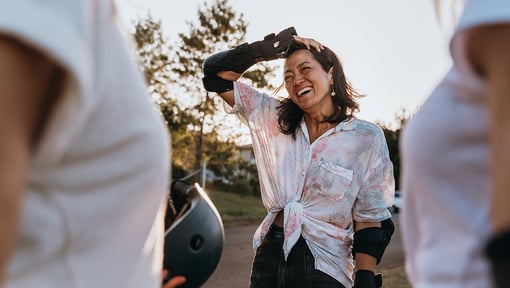 A woman outdoors wearing protective gear, pausing with a hand on the head after physical activity.