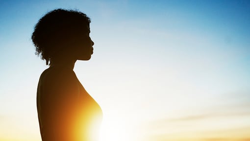 Silhouetted figure in profile standing outdoors against a bright sky, creating a calm, reflective scene.