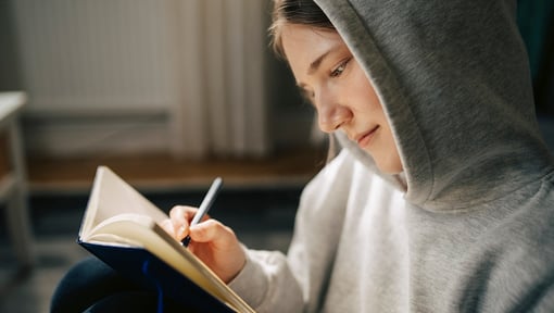 A woman writing in her journal while practicing self-compassion.