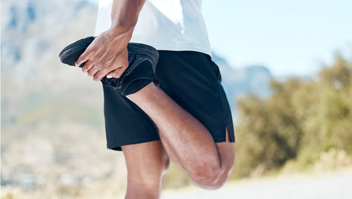 close up of a person standing while doing a quad stretch.