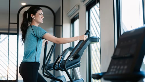 A woman using an elliptical machine in a gym during a low intensity steady state cardio workout