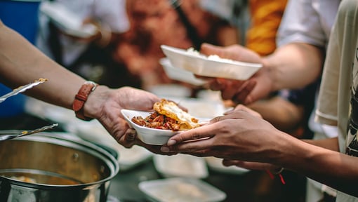 Hands passing a plate of food during a micro volunteering activity, highlighting small acts of service.