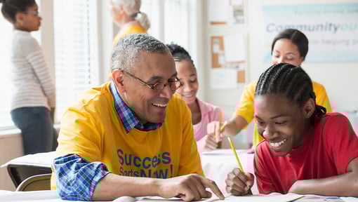 A teacher uses professional skills while volunteering time at a community learning table, providing one-on-one educational support to a student.