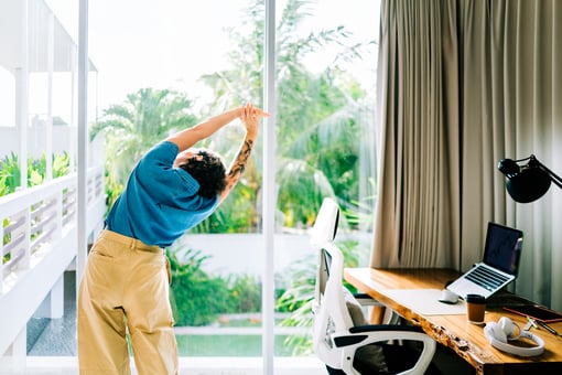 person doing some self care stretches next to their desk in their home office.