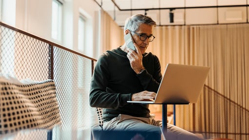A man sitting and working on a laptop in an office setting.
