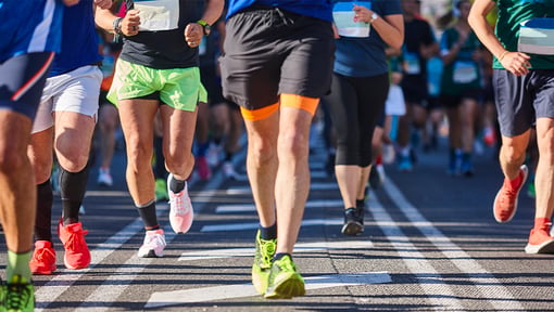 Participants running in a marathon on a city street, with runners in colorful athletic shoes and shorts.